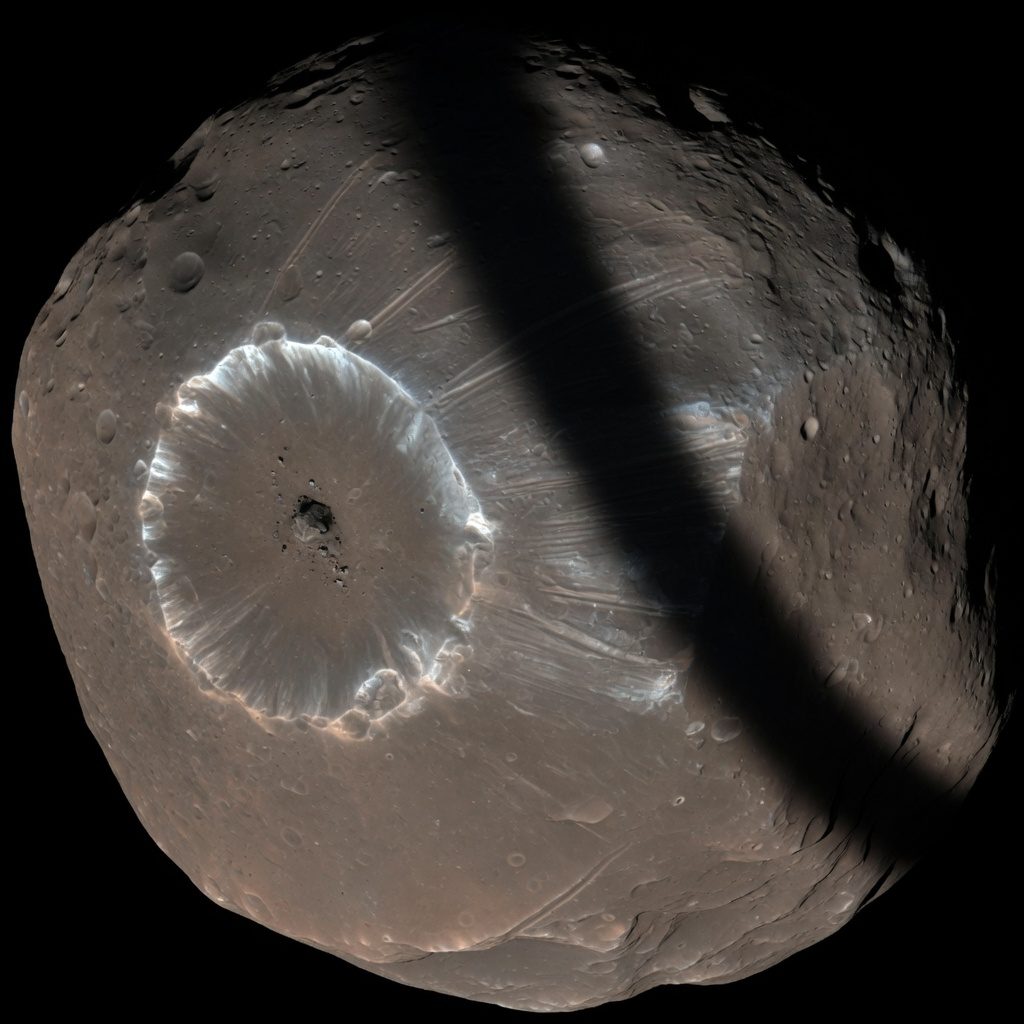 Illustration of an irregular cratered moon with a large crater and grooves.